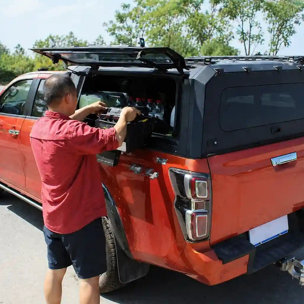 Contractor effortlessly accessing a tool box through the open gullwing side door of an ArmaCap heavy-duty steel truck canopy, highlighting convenient side access.