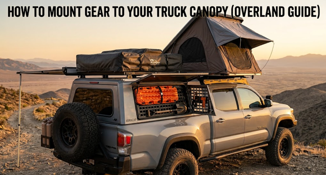A silver overland pickup truck with a rooftop tent and canopy-mounted gear on a desert trail.